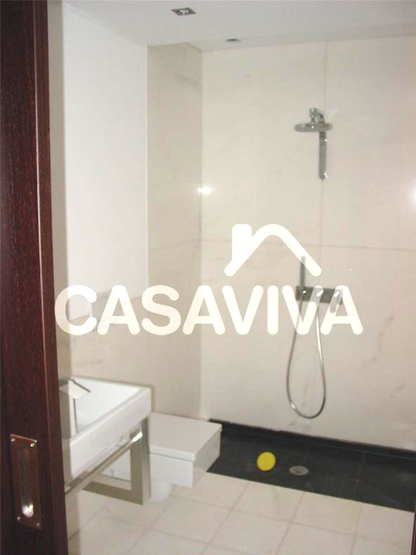 Casa de banho com base de duche, loias sanitrias suspensas, tecto falso e focos de luz embutidos.